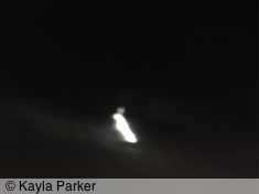 kayla's photo of full moon, visible as a white smudge with halo against black cloudy sky